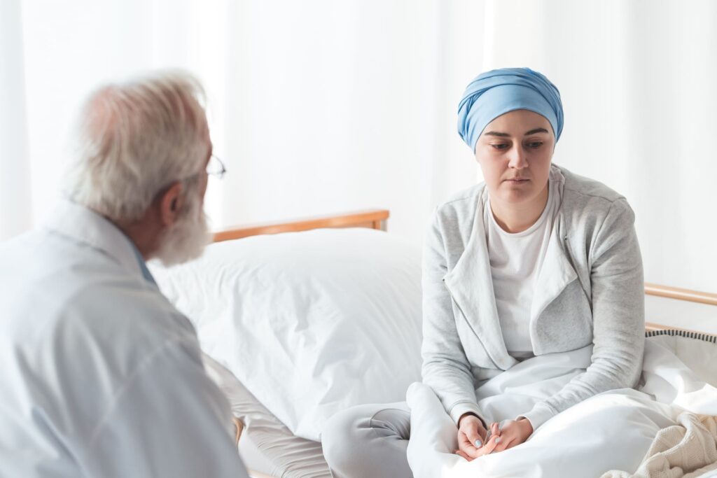 Medico che parla con paziente oncologico visibilmente preoccupato.