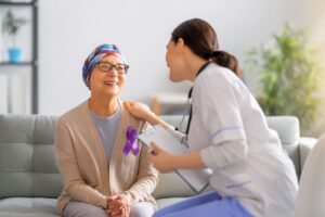 Medico che comunica in modo empatico con la paziente oncologica toccandole la spalla in segno di vicinanza.