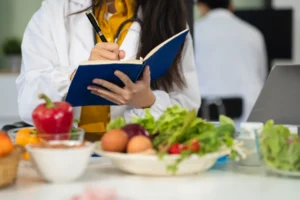 Un medico prende appunti in un'agenda con dei piatti di verdura di fronte.